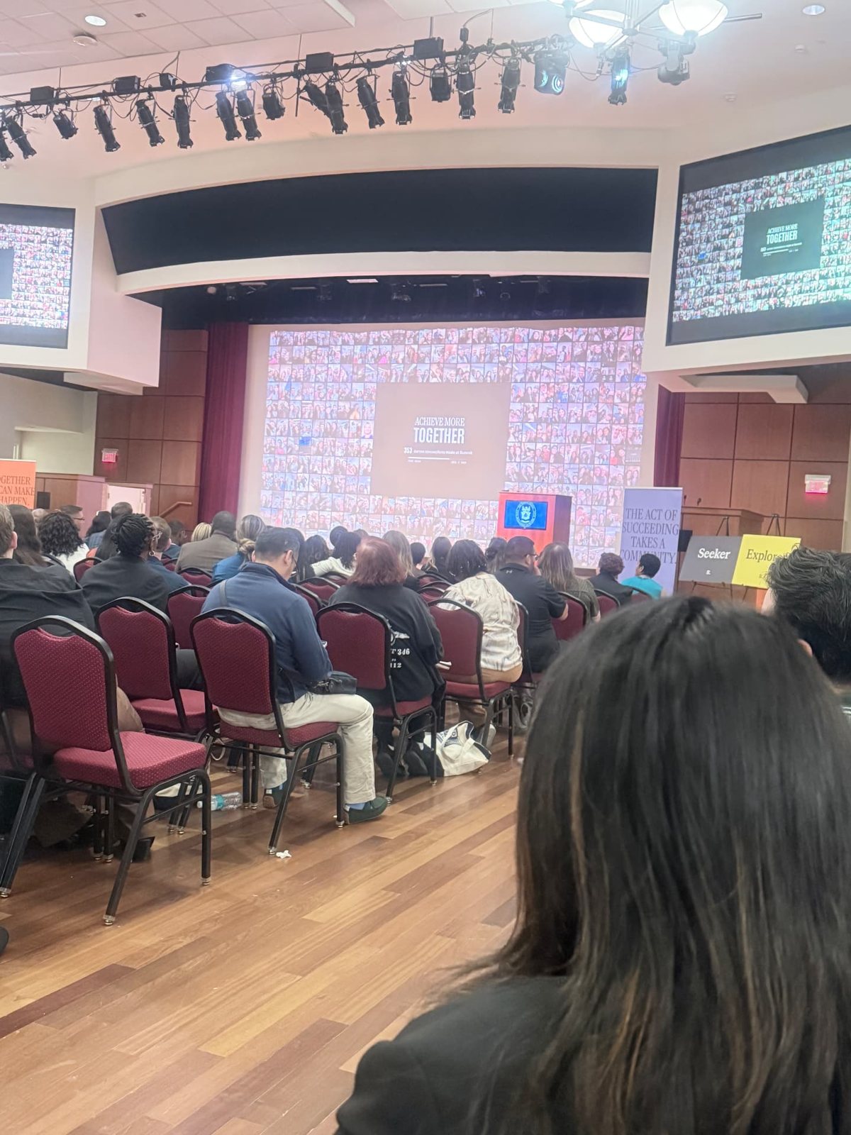 The main room filling up with attendees under the summit screens