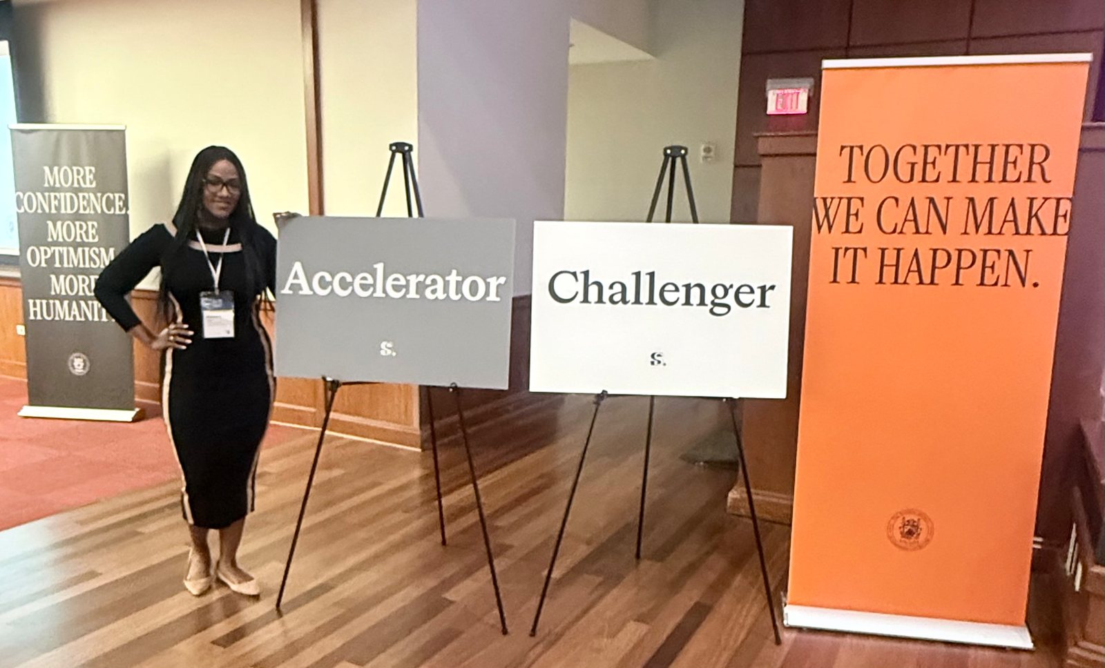 Kimberly standing beside interactive signs labeled Accelerator and Challenger and a banner reading Together we can make it happen
